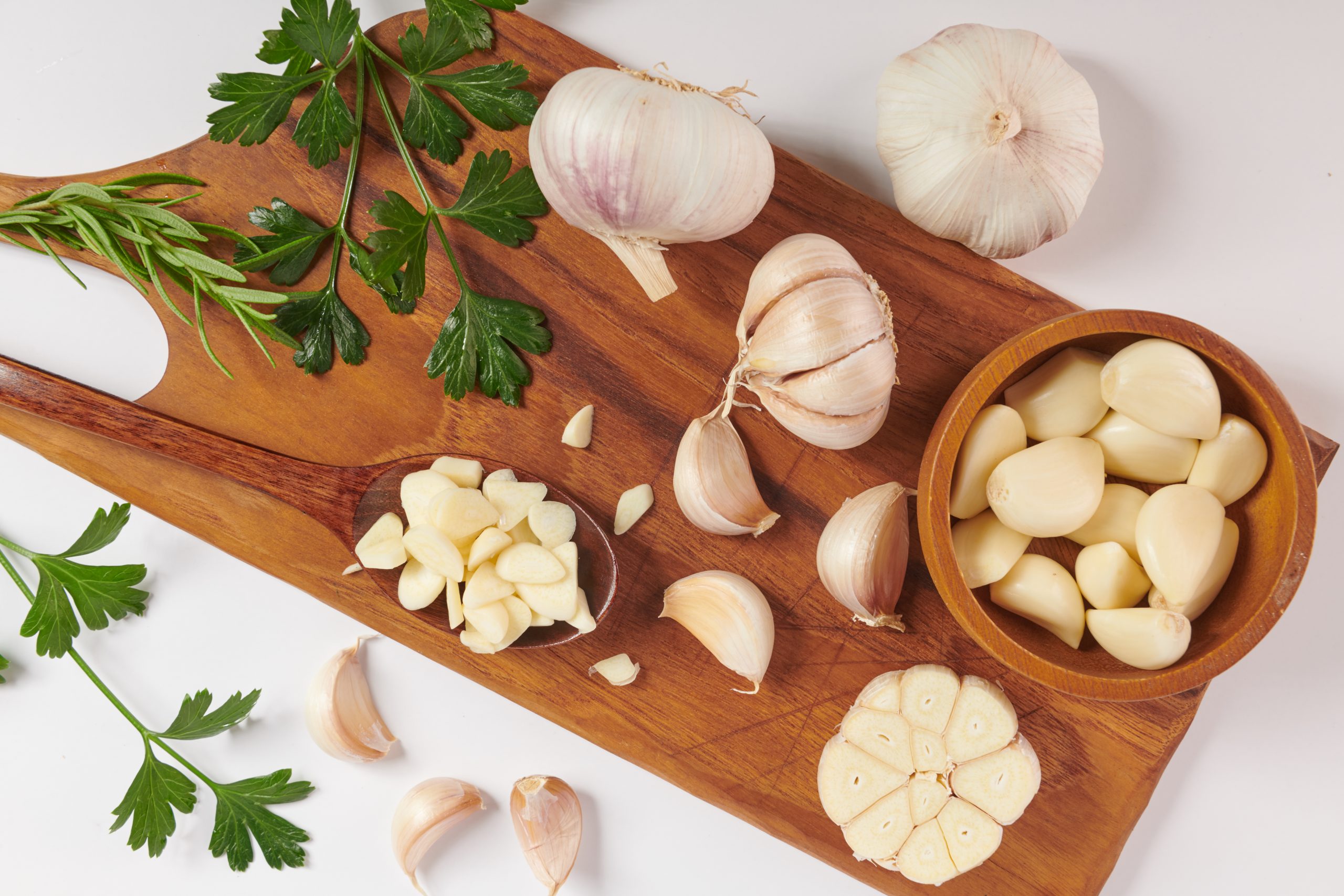 garlic with rosemary, parsley and peppercorn  on a wooden board isolated on white background. Top view. Flat lay pattern. freshly picked from home growth organic garden. Food concept.